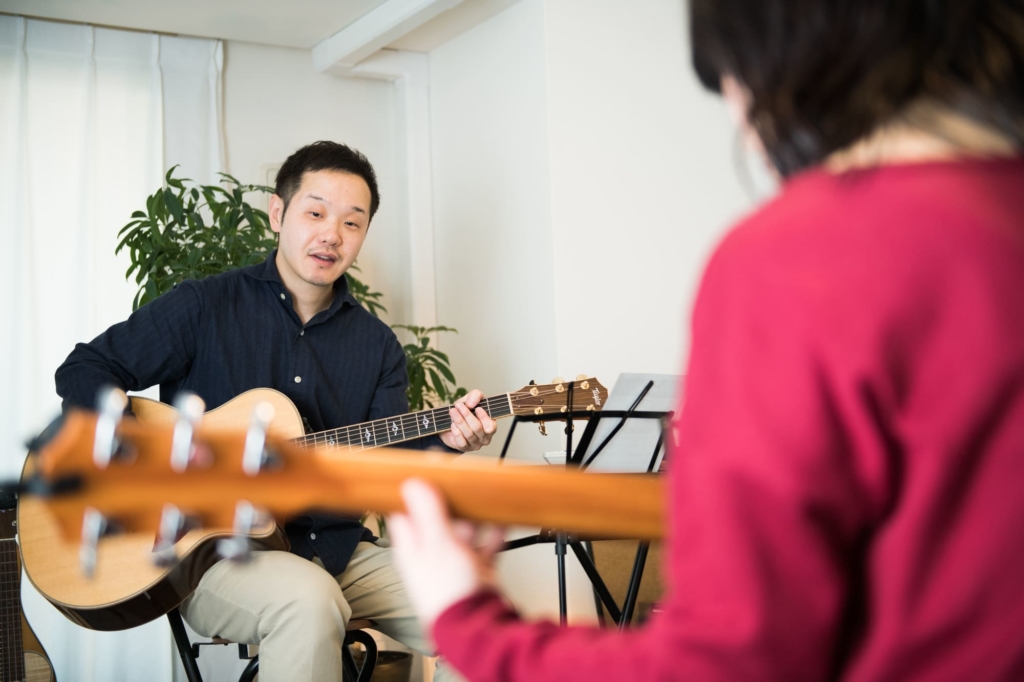 ギターを教える男性と習う女性